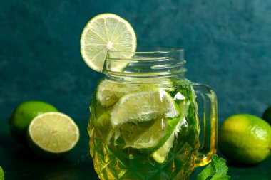 Mason kavanozu soğuk mojito ve yeşil masada limon.