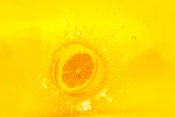 熟したレモンの部分が黄色のジュースに落ちる — ストック写真