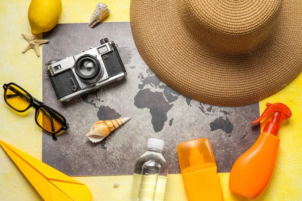 世界地图 防晒霜瓶 照相相机和黄色背景帽子的组合 — 图库照片