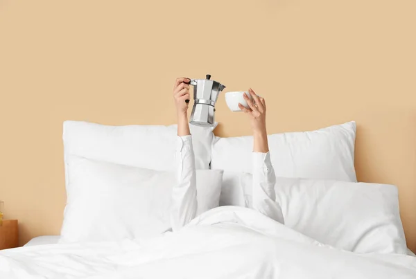 一个拿着咖啡壶和杯子躺在床上的年轻女人的早晨 — 图库照片