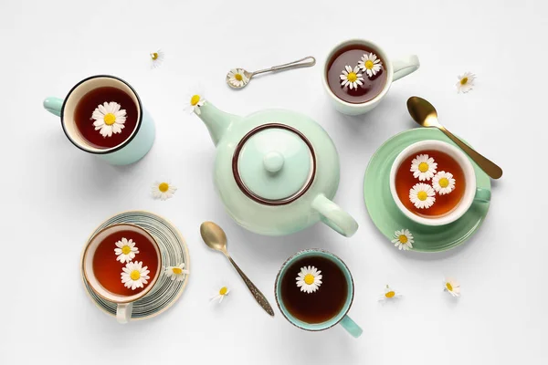 stock image Teapot with cups of natural chamomile tea and flowers on white background