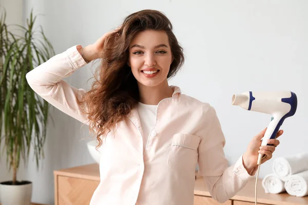 stock image Pretty young woman with hair dryer in bathroom