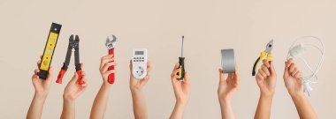 Işık arka planında elektrikçi malzemeleri olan kadın eller.