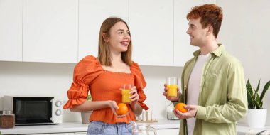 Mutfakta meyve suyu ve portakallı mutlu bir çift.