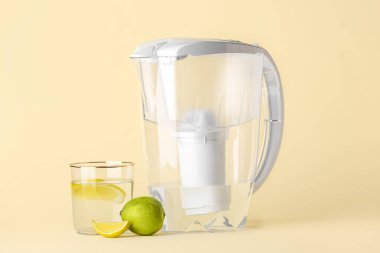 Bej arka planda narenciye dilimli su filtresi sürahi ve cam.