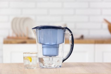Modern mutfaktaki masada limon dilimli su filtresi sürahi ve cam.
