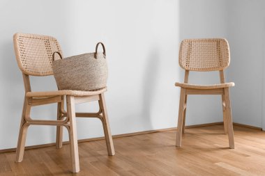 Işık duvarının yanında sepeti olan hasır sandalyeler.