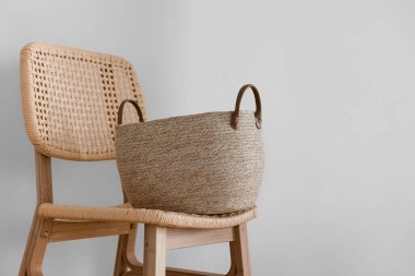 Işık duvarının yanında sepeti olan hasır sandalye.