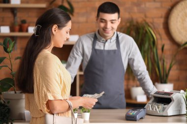 Çiçekçide dolar banknotları olan genç bir kadın.