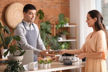 Çiçekçide dolar banknotlarıyla ödeme yapan genç bir kadın.