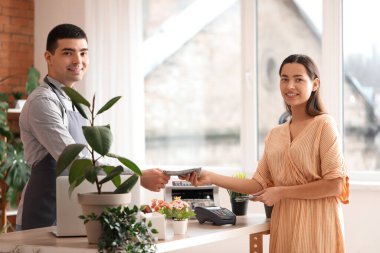Çiçekçide dolar banknotlarıyla ödeme yapan genç bir kadın.