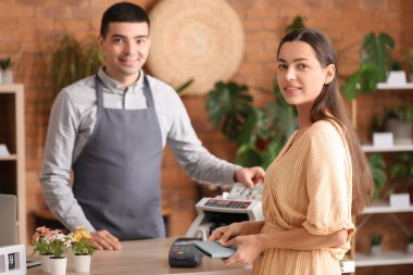 Erkek kasiyer çiçekçide para sayma makinesi kullanıyor.