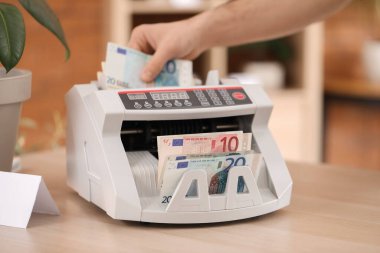 Erkek kasiyer çiçekçide para sayma makinesi kullanıyor, yakın plan.