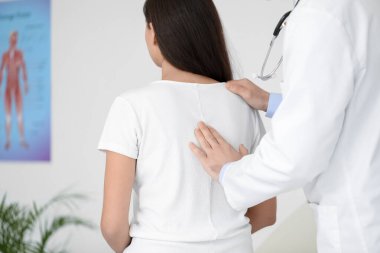Erkek doktor klinikteki genç kadının duruşunu kontrol ediyor.
