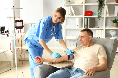 Klinikte olgun donörden kan alan kadın hemşire.