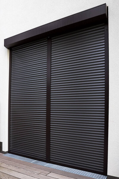 View of building with big windows and black roller shutters outdoors