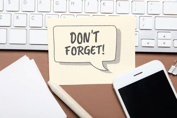 Reminder with mobile phone and computer keyboard on brown background, closeup
