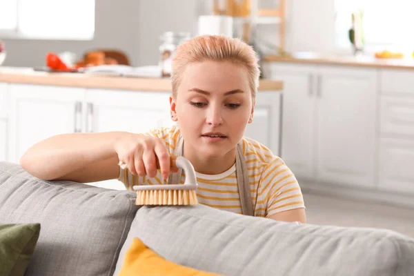 Młoda Kobieta Sprzątanie Sofa Szczotką Domu — Zdjęcie stockowe