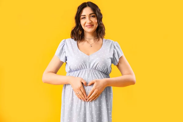 若いです妊娠中の女性黄色の背景 — ストック写真