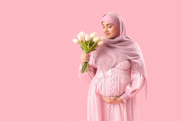 若いです妊娠中のイスラム教徒女性とともにチューリップオンピンクの背景 — ストック写真
