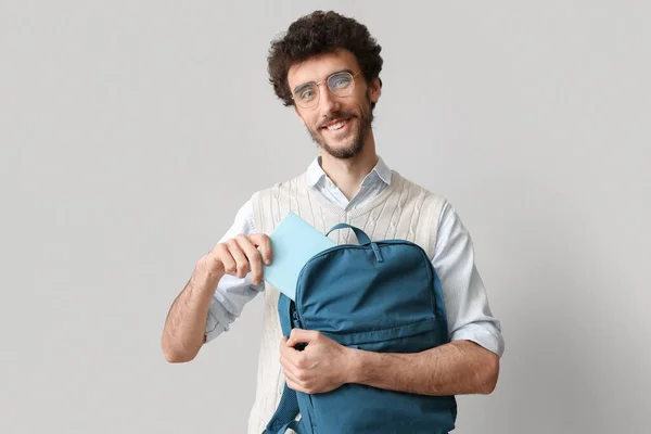 Male Student Putting Book Backpack Light Background — Stock Photo, Image