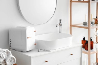 Yüz masajı aletli kozmetik buzdolabı ve banyodaki çekmecelerde lavabo.