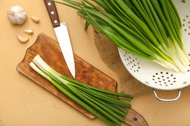 Bej arka planda taze yeşil soğanlı ahşap tahta.