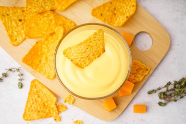 Lezzetli çedar peyniri sosu ve beyaz grunge arkaplanlı nacho tabağı.