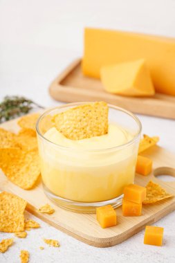 Lezzetli çedar peyniri sosu ve beyaz grunge arkaplanlı nacho tabağı.