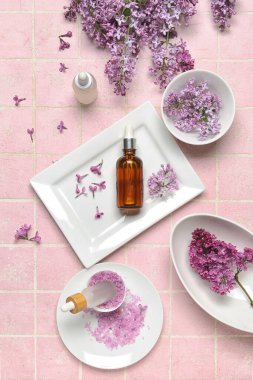 Pembe arka planda eflatun yağı, deniz tuzu ve çiçek içeren kompozisyon