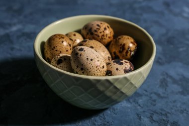 Mavi arka planda taze bıldırcın yumurtalı kase.