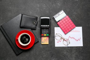 Ödeme terminali olan kredi kartı, bir fincan kahve ve hesap makinesi siyah masada.