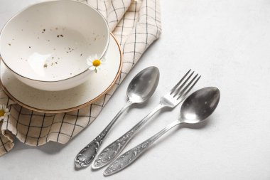 Gümüş çatal bıçaklı tabaklar ve beyaz arka planda peçete.