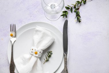 Katlanmış peçeteli tabaklar, gümüş çatal bıçak takımı ve grunge beyaz arka planda cam.