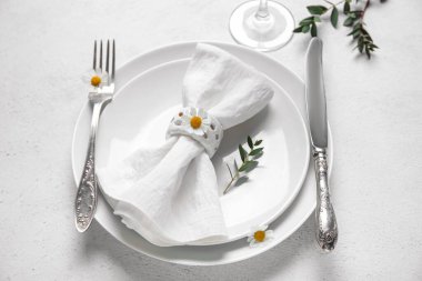 Katlanmış peçeteli tabaklar, gümüş çatal bıçak takımı ve grunge beyaz arka planda cam.