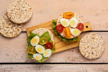 Bıldırcın yumurtalı pirinç krakerleri, domatesler ve hafif ahşap arka planda marul.