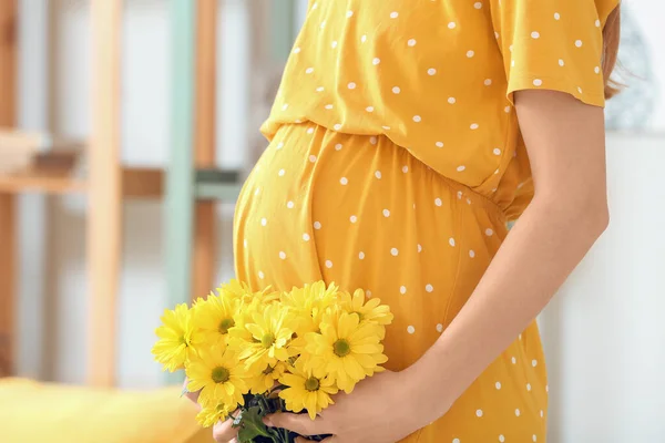 Ung Gravid Kvinne Med Krysantemumblomster Hjemme – stockfoto