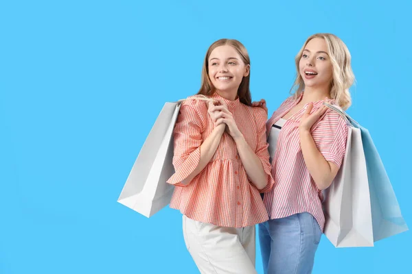 Junge Schwestern Mit Einkaufstaschen Auf Blauem Hintergrund — Stockfoto