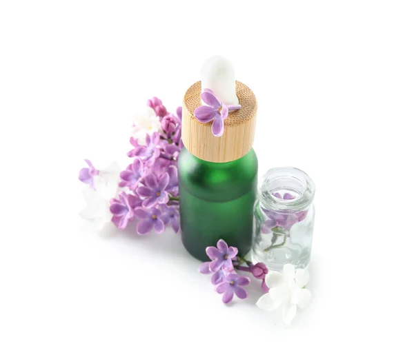 stock image Bottles of cosmetic oil with beautiful lilac flowers on white background