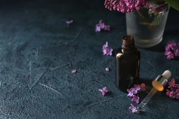 Μπουκάλι Καλλυντικό Λάδι Όμορφα Λιλά Λουλούδια Σκούρο Τραπέζι — Φωτογραφία Αρχείου