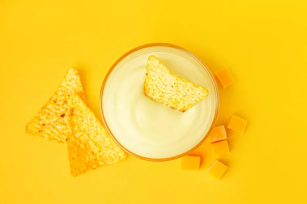 stock image Bowl with tasty cheddar cheese sauce and nachos on yellow background