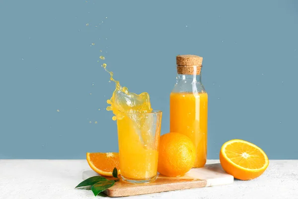 Μπουκάλι Και Ποτήρι Φρέσκο Χυμό Πορτοκαλιού Πιτσιλιές Στο Τραπέζι Μπλε — Φωτογραφία Αρχείου