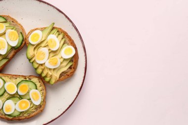 Hafif arkaplanda bıldırcın yumurtası, avokado ve salatalıklı lezzetli tostlar.