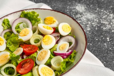 Bıldırcın yumurtalı, domatesli, soğanlı ve marullu lezzetli salata, yakın plan.