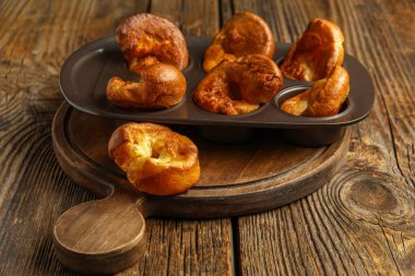 Ahşap arka planda lezzetli Yorkshire pudingi olan teneke fırın.