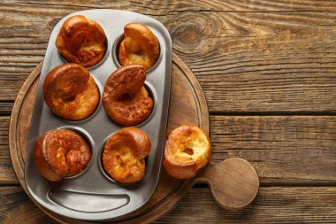 Ahşap arka planda lezzetli Yorkshire pudingi olan teneke fırın.