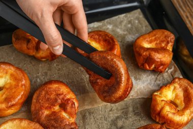 Lezzetli Yorkshire pudingini yemek tepsisinden alan kadın.