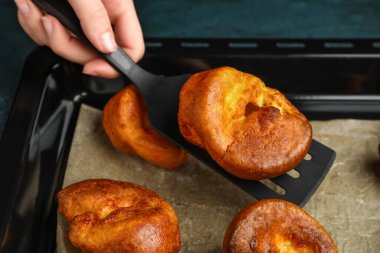 Lezzetli Yorkshire pudingini yemek tepsisinden alan kadın, yakın plan.