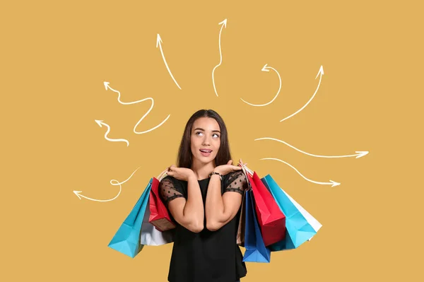 黄色の背景にショッピングバッグを持つ思慮深い若い女性 — ストック写真