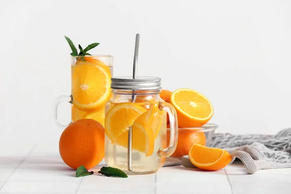 白のタイルテーブルの上にオレンジのスライスと注入水のメイソンジャーとガラス — ストック写真